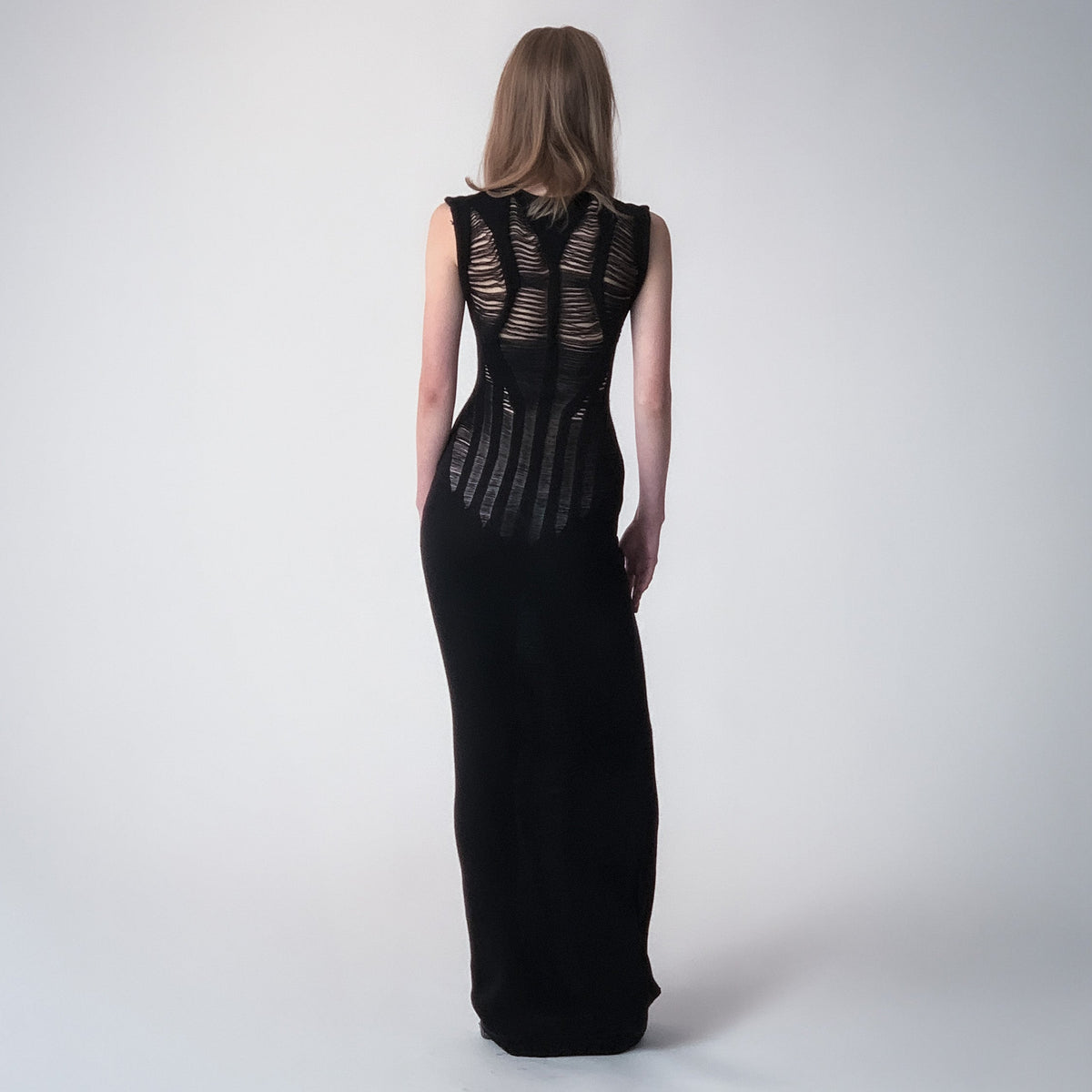 Long black knitted dress with floats details on a light grey background 