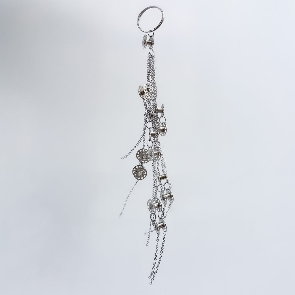 Metal bag charm on a light gray background