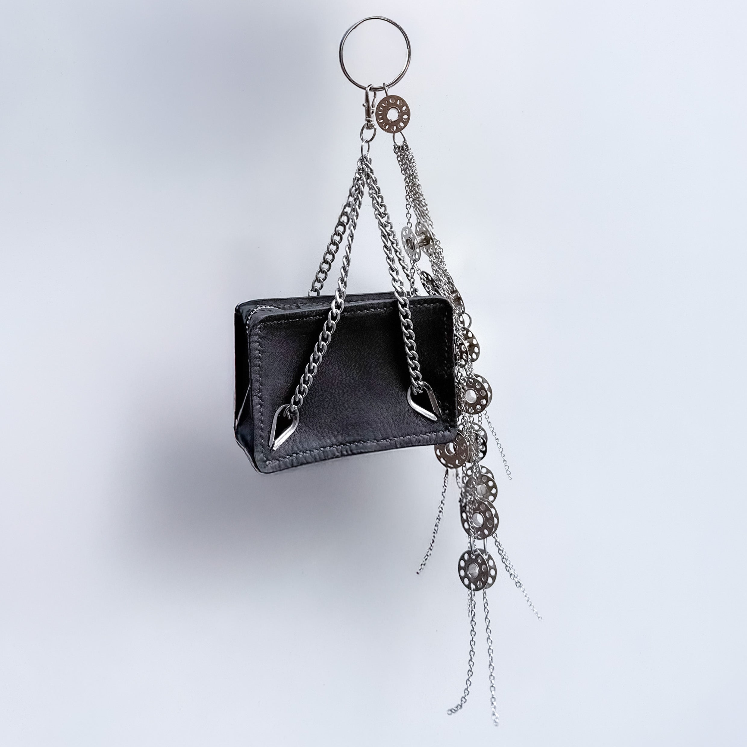 mini black leather bag with metal chain handles as a bag charm  with a decorative keychain with metal bobbins and chains